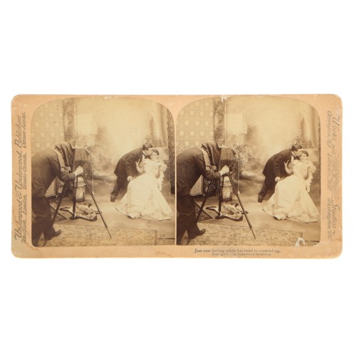 Vista estereoscopica Underwood fotógrafo retratando. "Just one, darling, while his head is covered up"