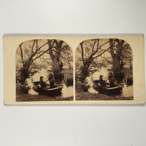 Vista estereo de cartón _ Personajes en un bote de remos junto a una orilla arbolada.