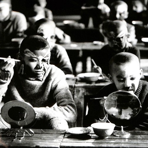 Fotografía en blanco y negro de niños actores de la Ópera de Pekín maquillándose