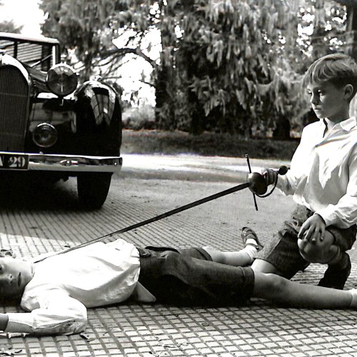 Fotografía en blanco y negro de dos niños jugando a espadachines