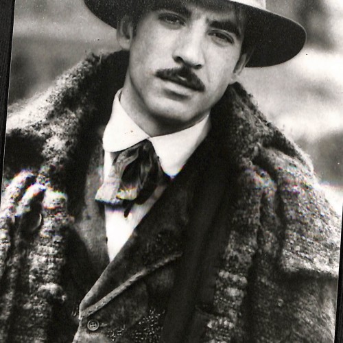 Fotografía en blanco y negro de un hombre con sombrero y abrigo