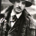 Fotografía en blanco y negro de un hombre con sombrero y abrigo