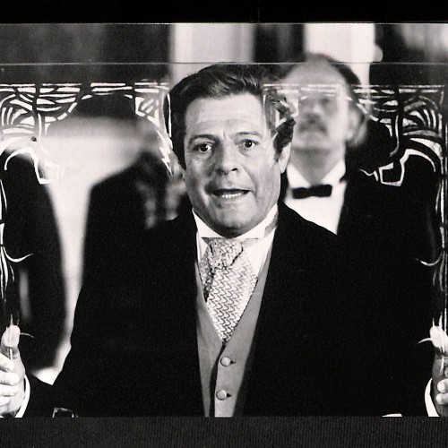 Fotografía en blanco y negro del actor italiano Marcello Mastroianni sosteniendo un cristal decorado