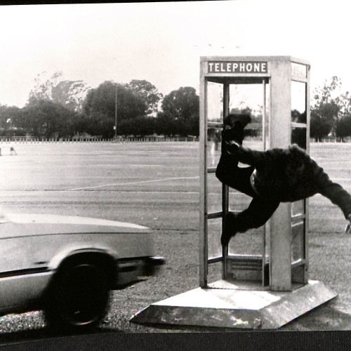 Fotografía en blanco y negro de escena de acción cinematográfica con coche y cabina telefónica