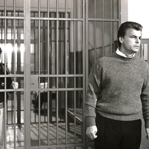 Fotografía en blanco y negro, escena cinematográfica con hombre frente a rejas